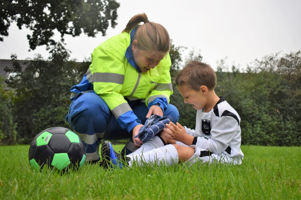 EHBO bij kinderen koelen kneuzing bij het voetballen.